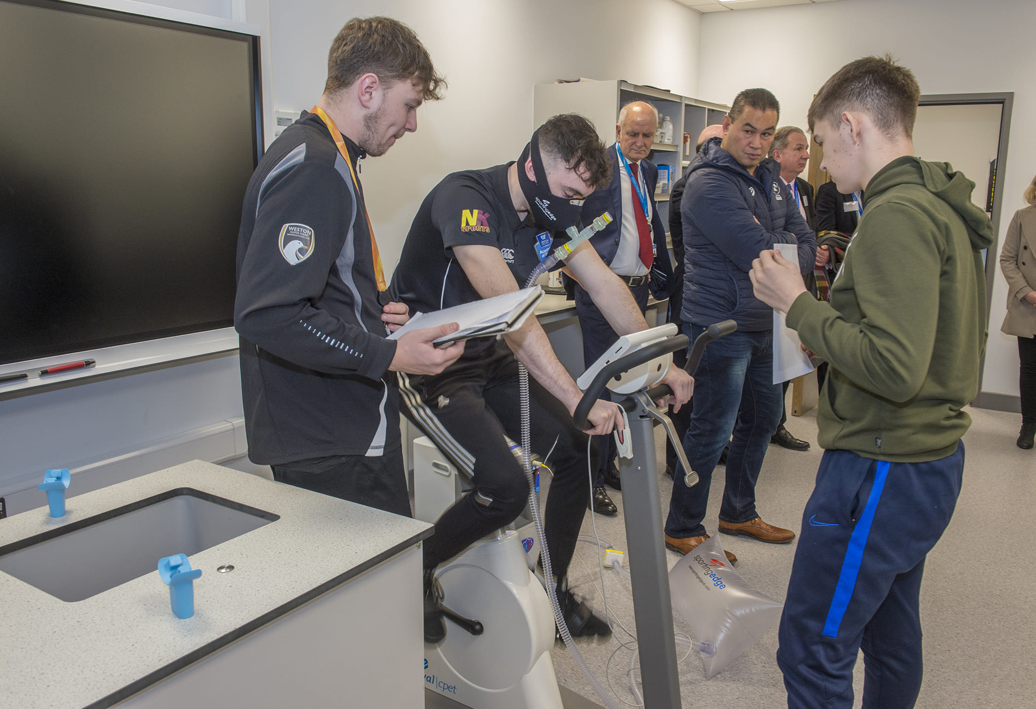 a boy uses a exercise bike while a group watches