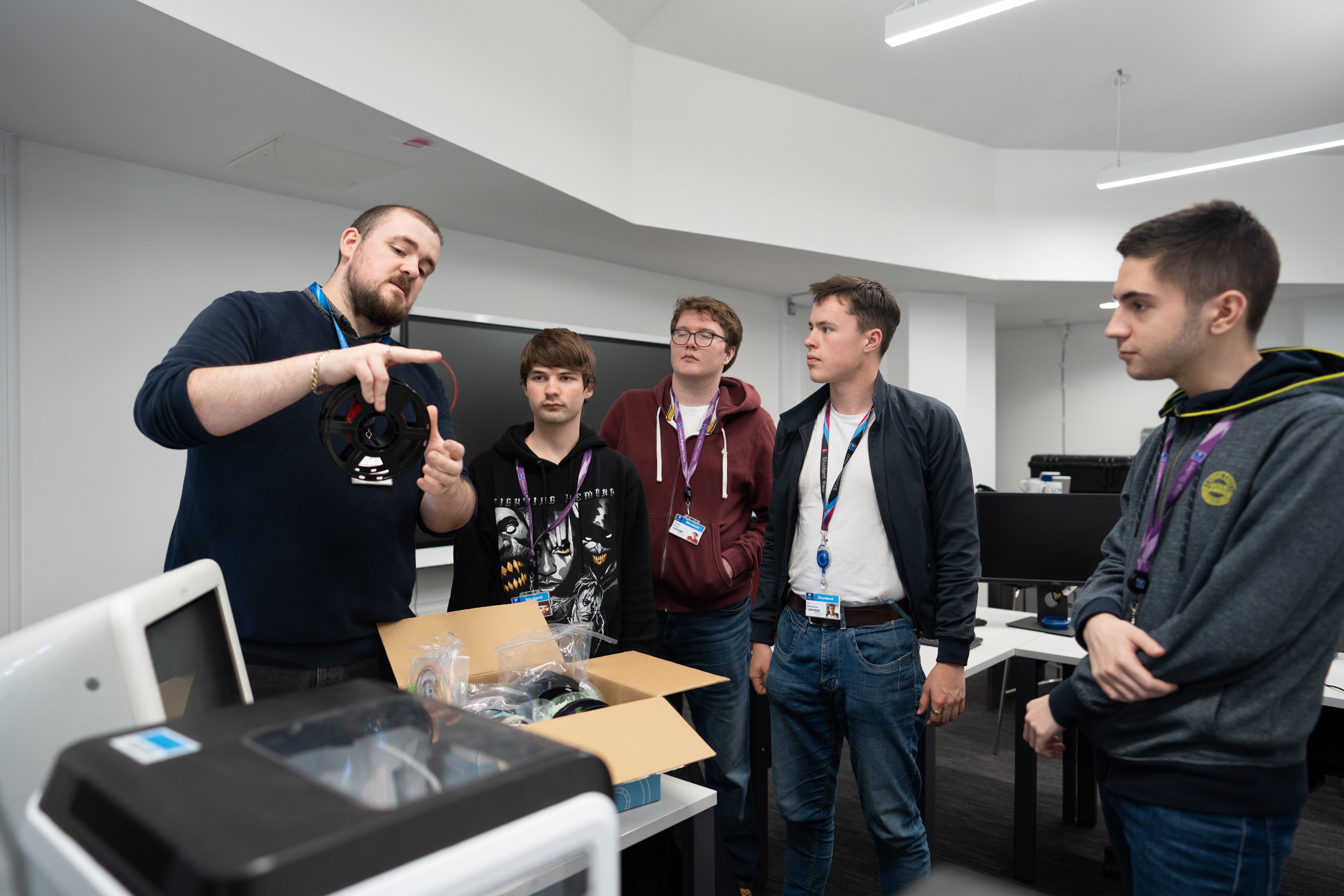 lecturer shows a PC fan to a group of students