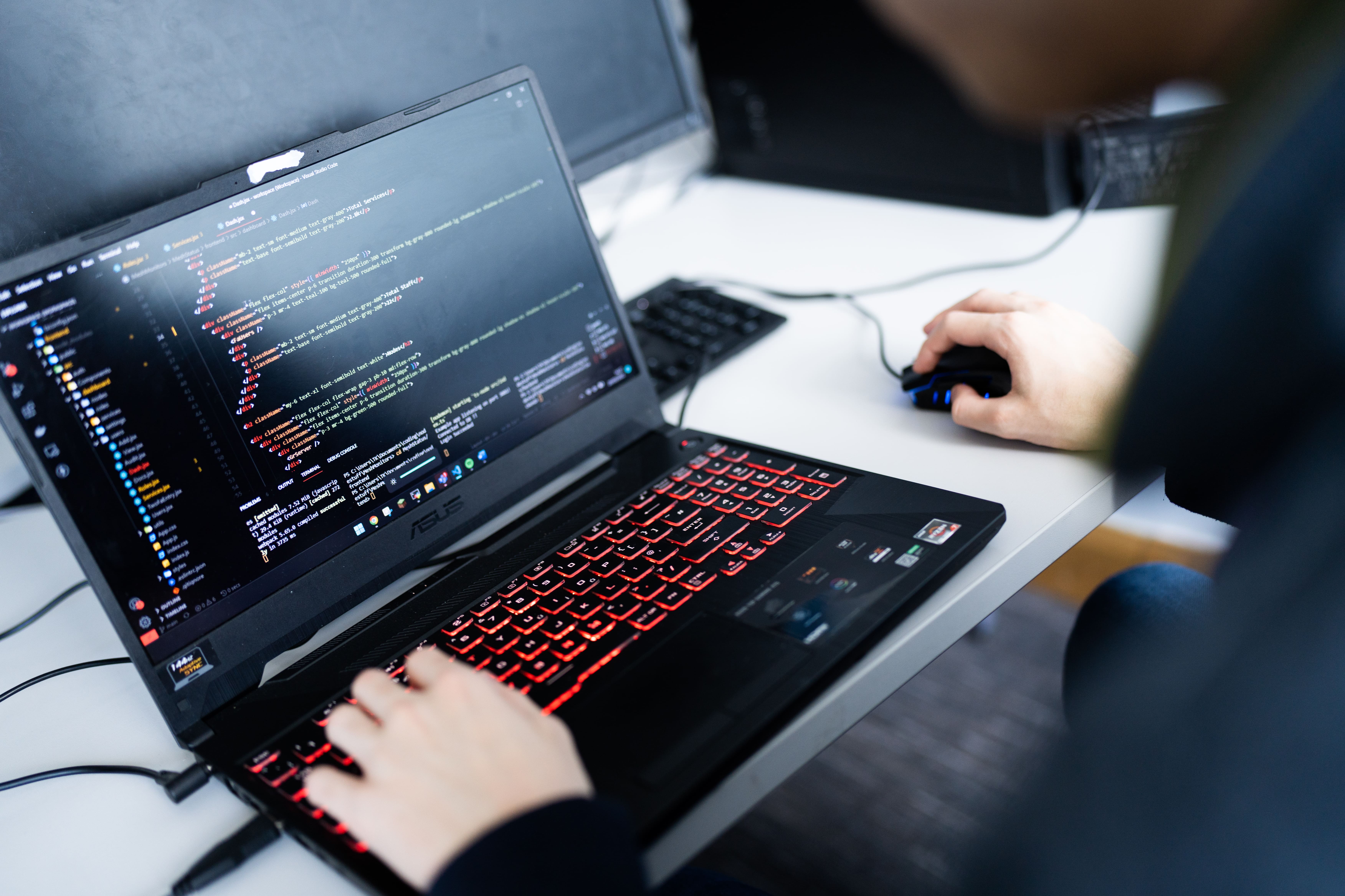 closeup of student coding HTML on a laptop
