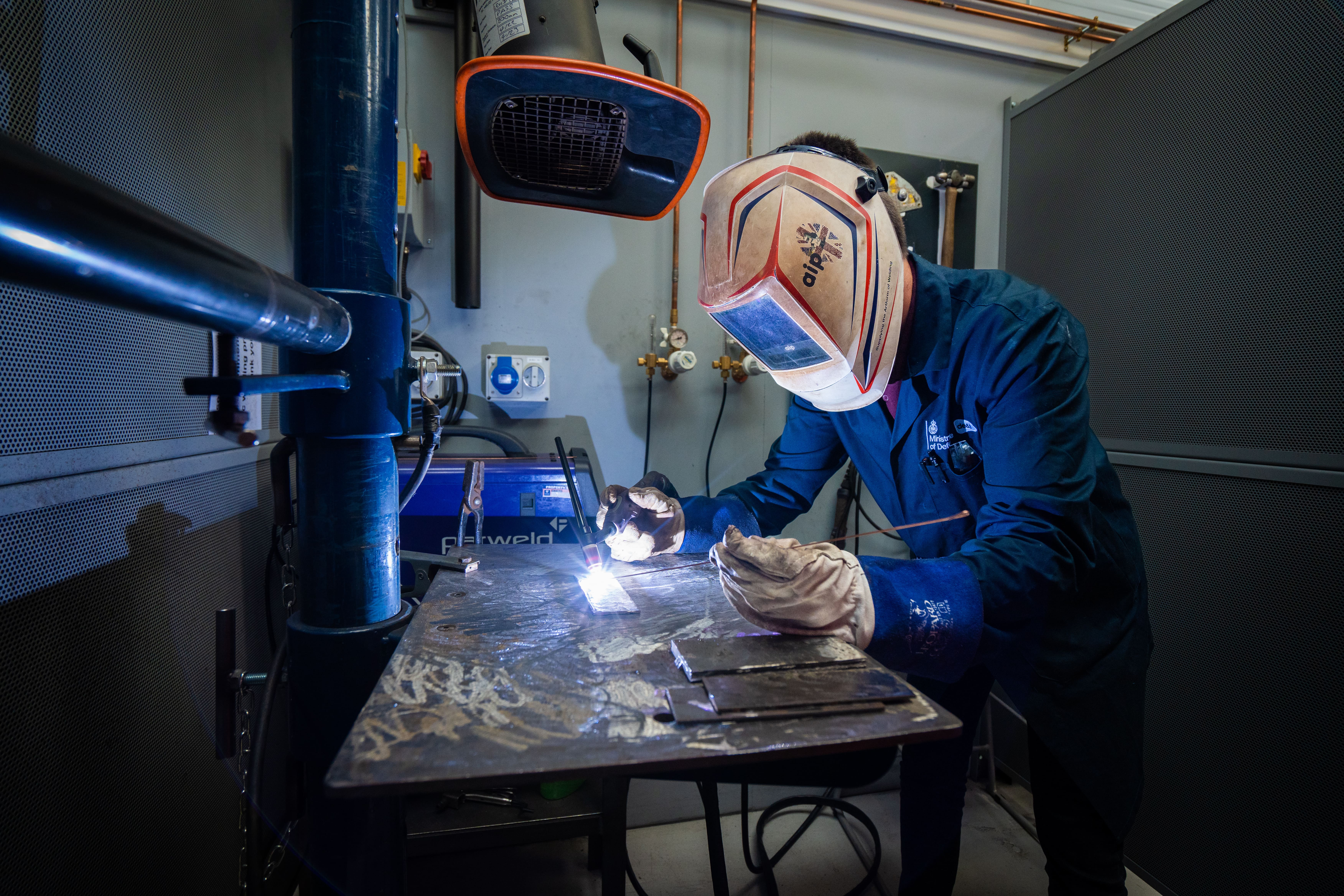 student with full face mask welds copper