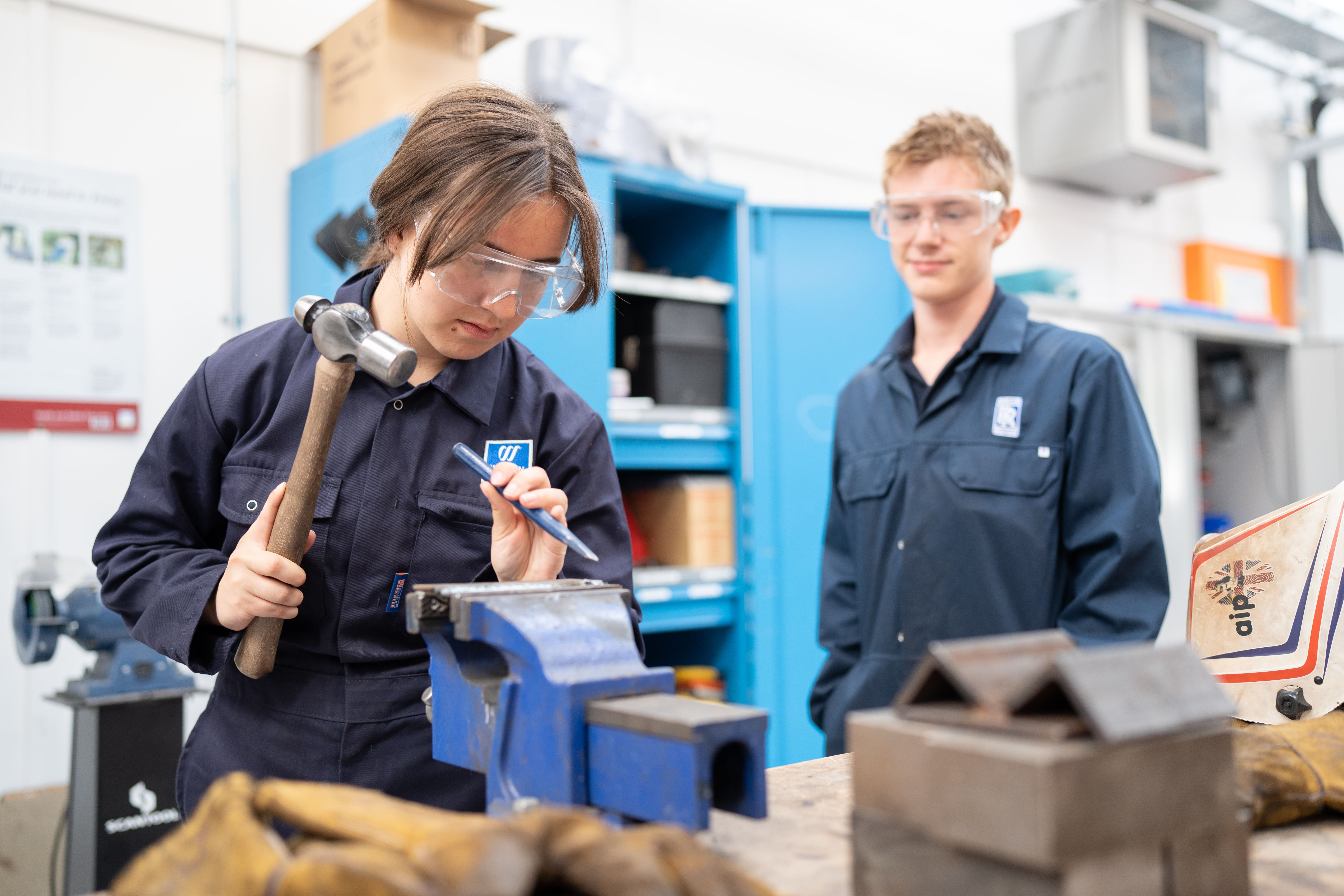 student using chisel and hammer on object in a vice