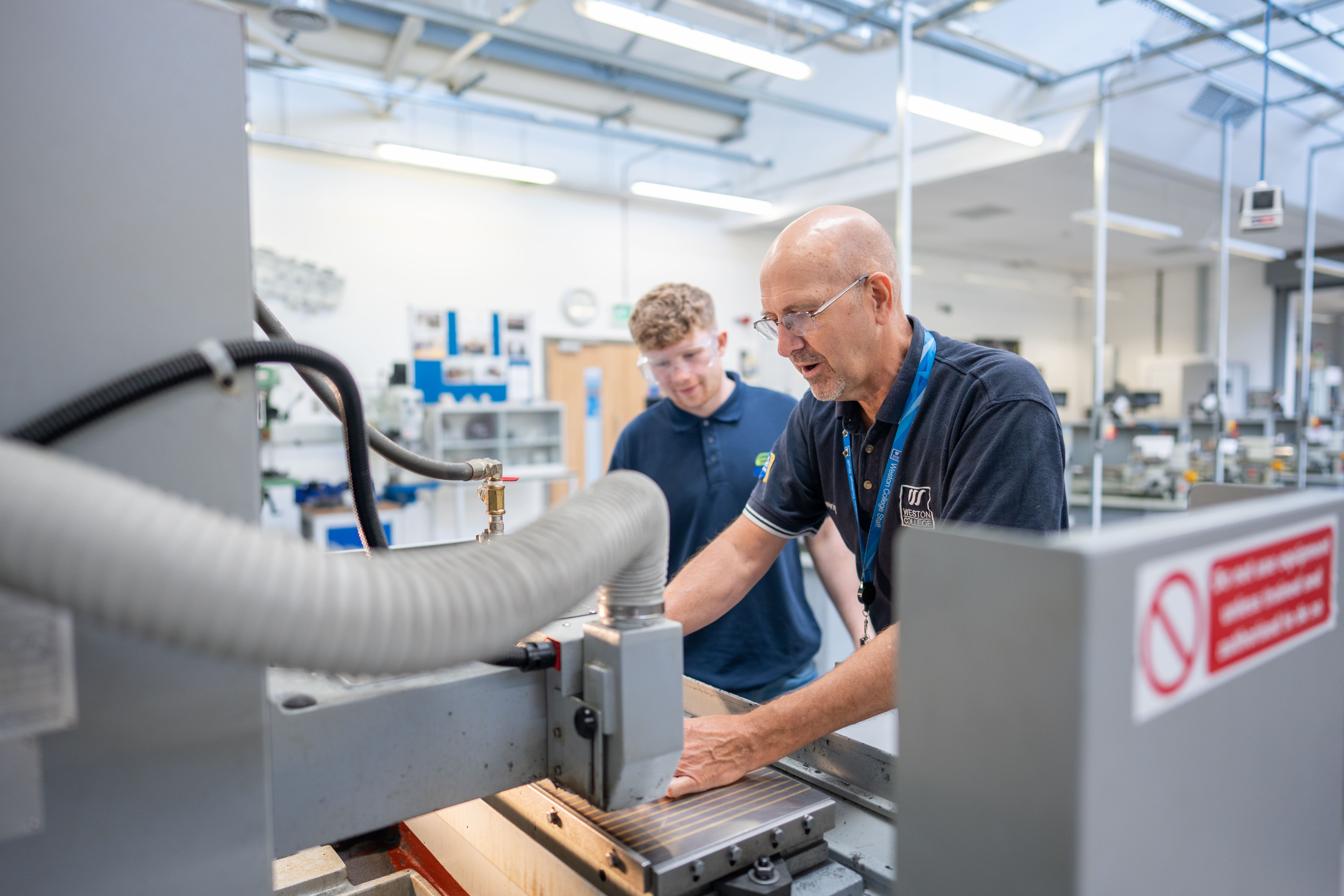 lecturer demonstrates how machine works to a student