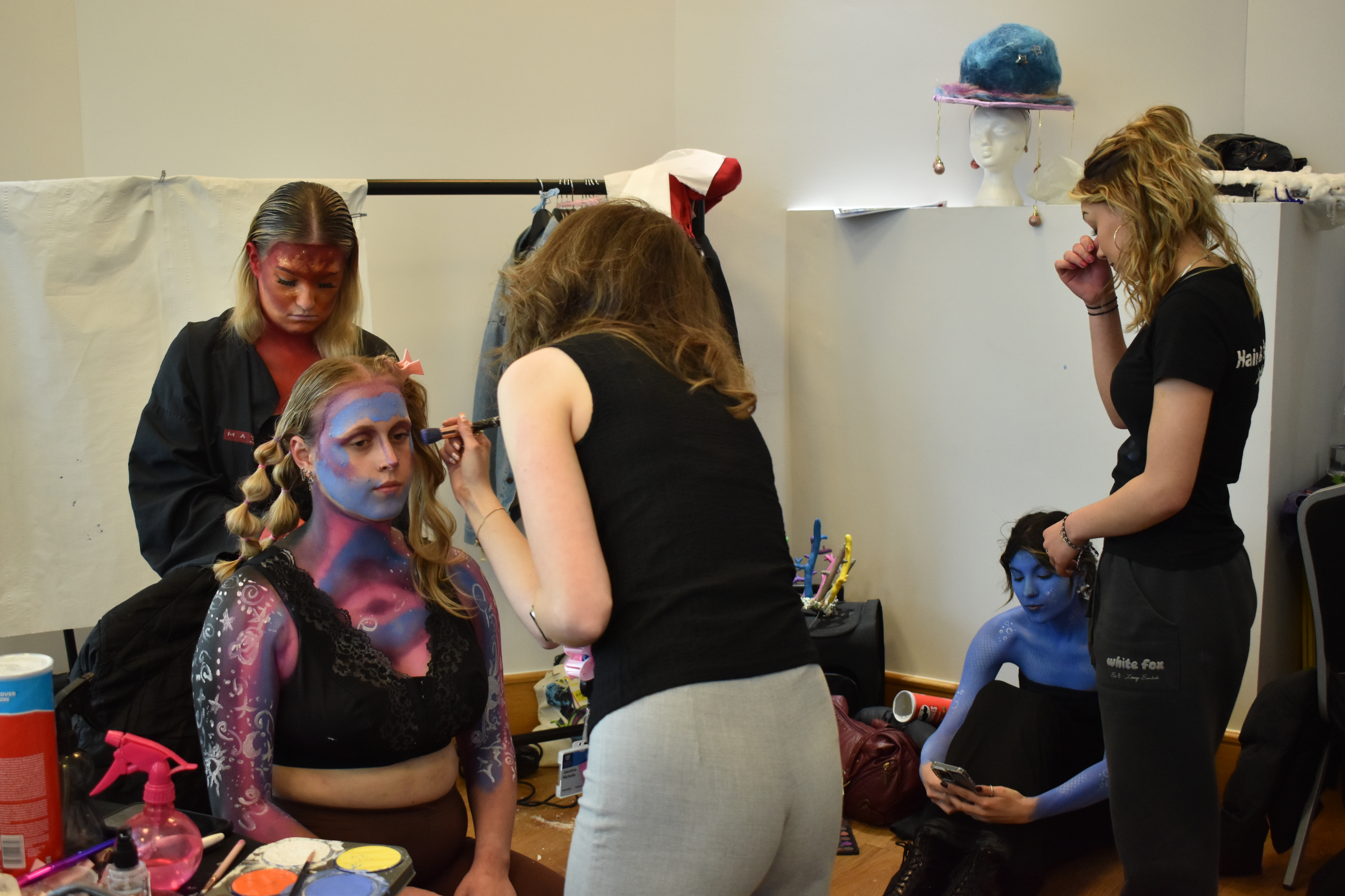 Makeup artists applying body paint to models