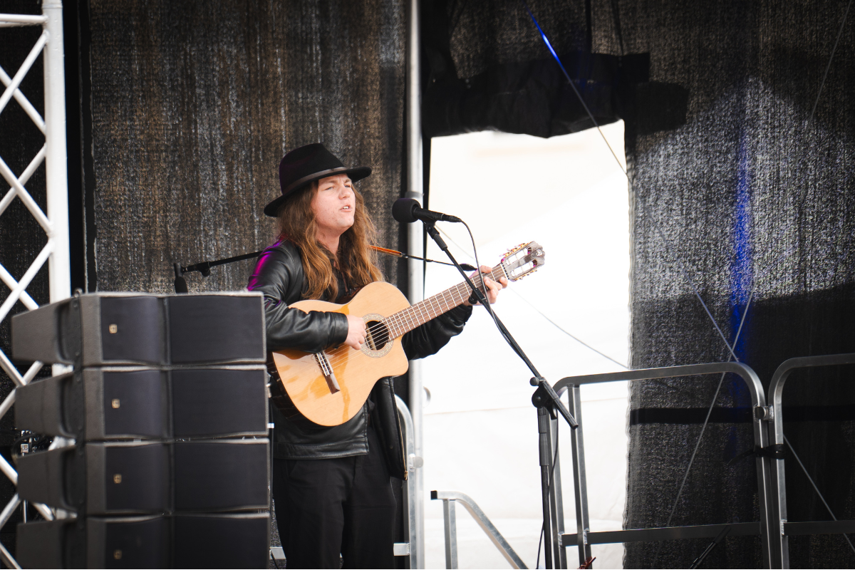 Music student performing with acoustic guitar on stage