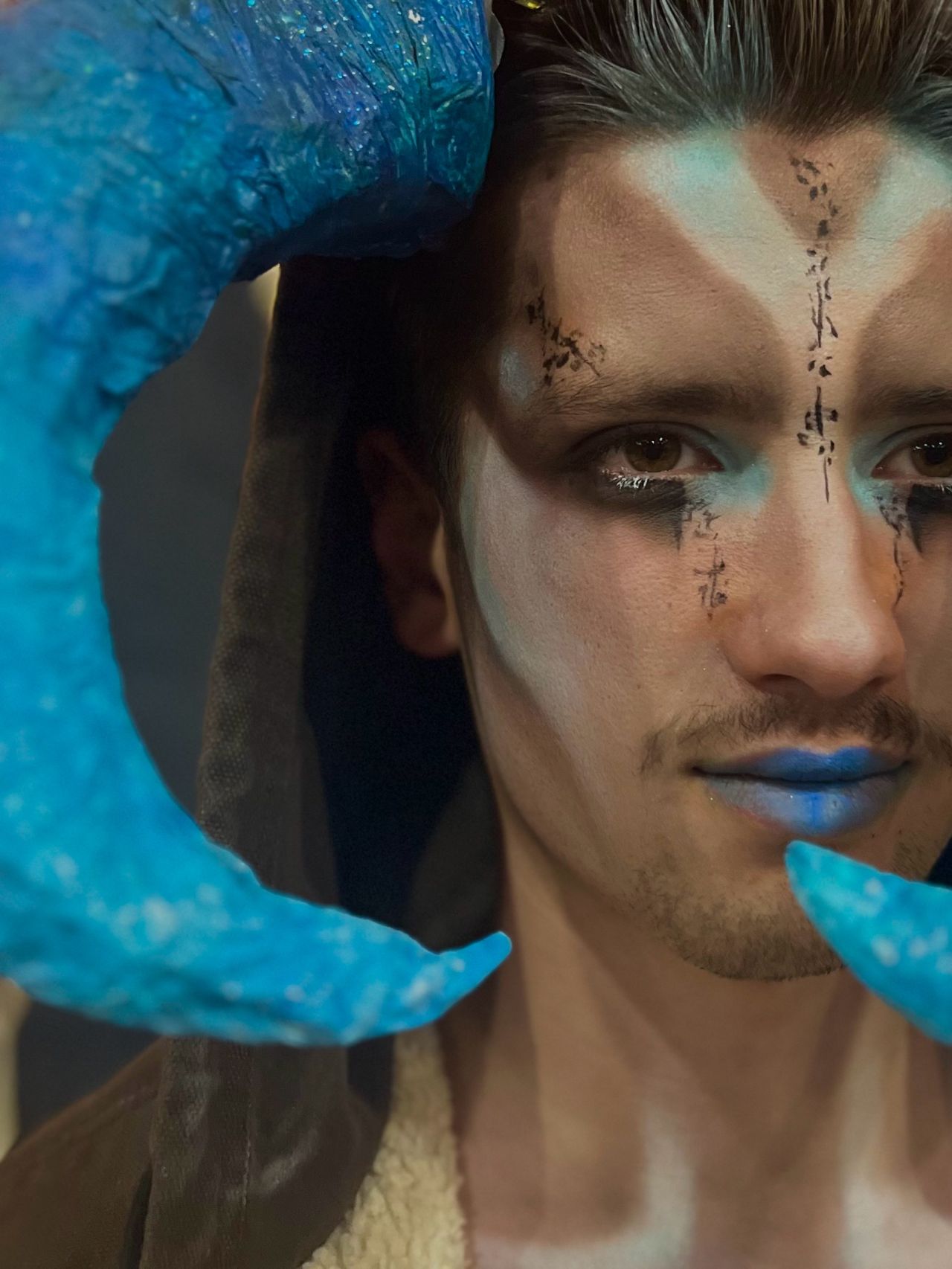 Student with fantasy makeup and face paint with blue horns