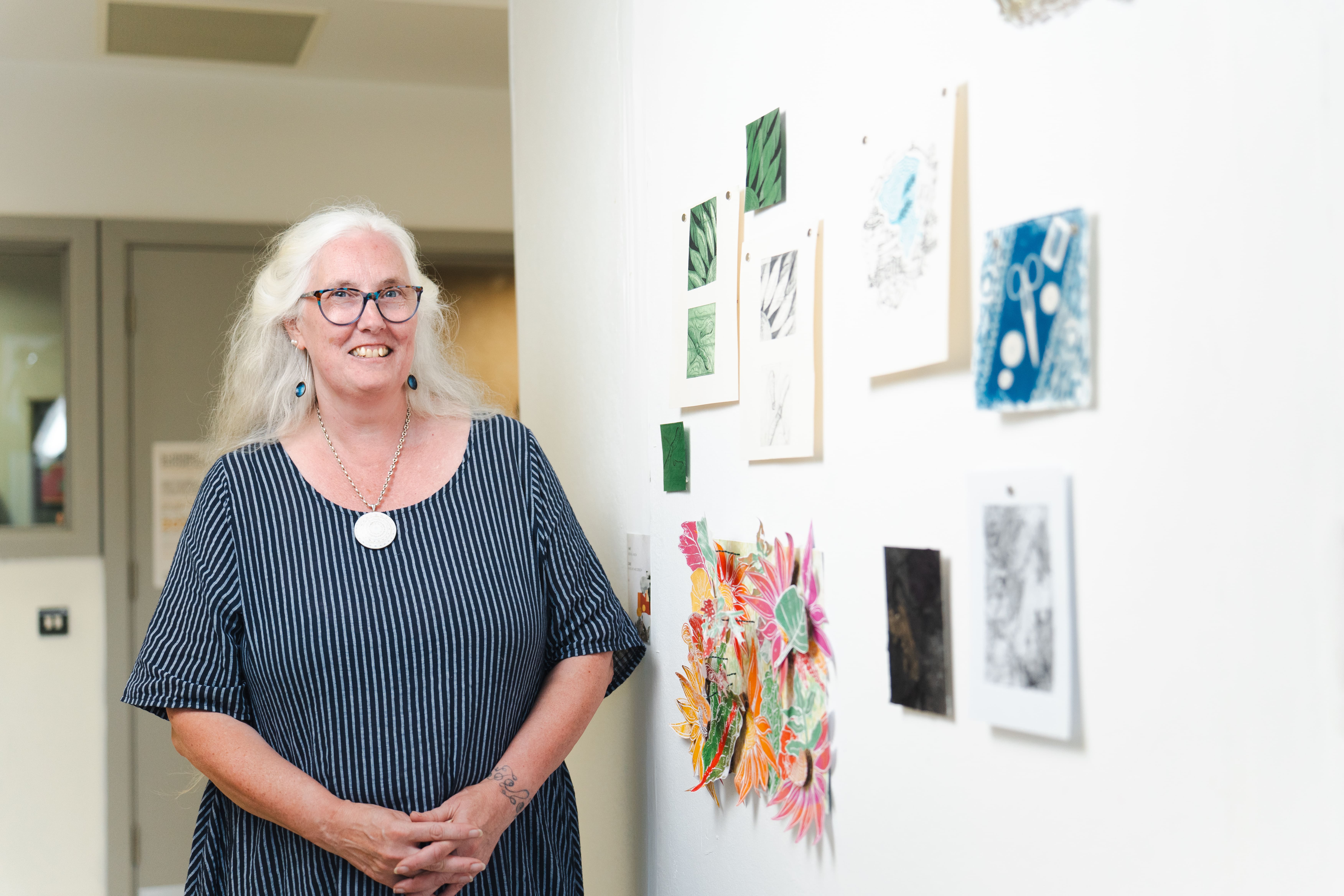 a women stands next to her mixture of paintings 
