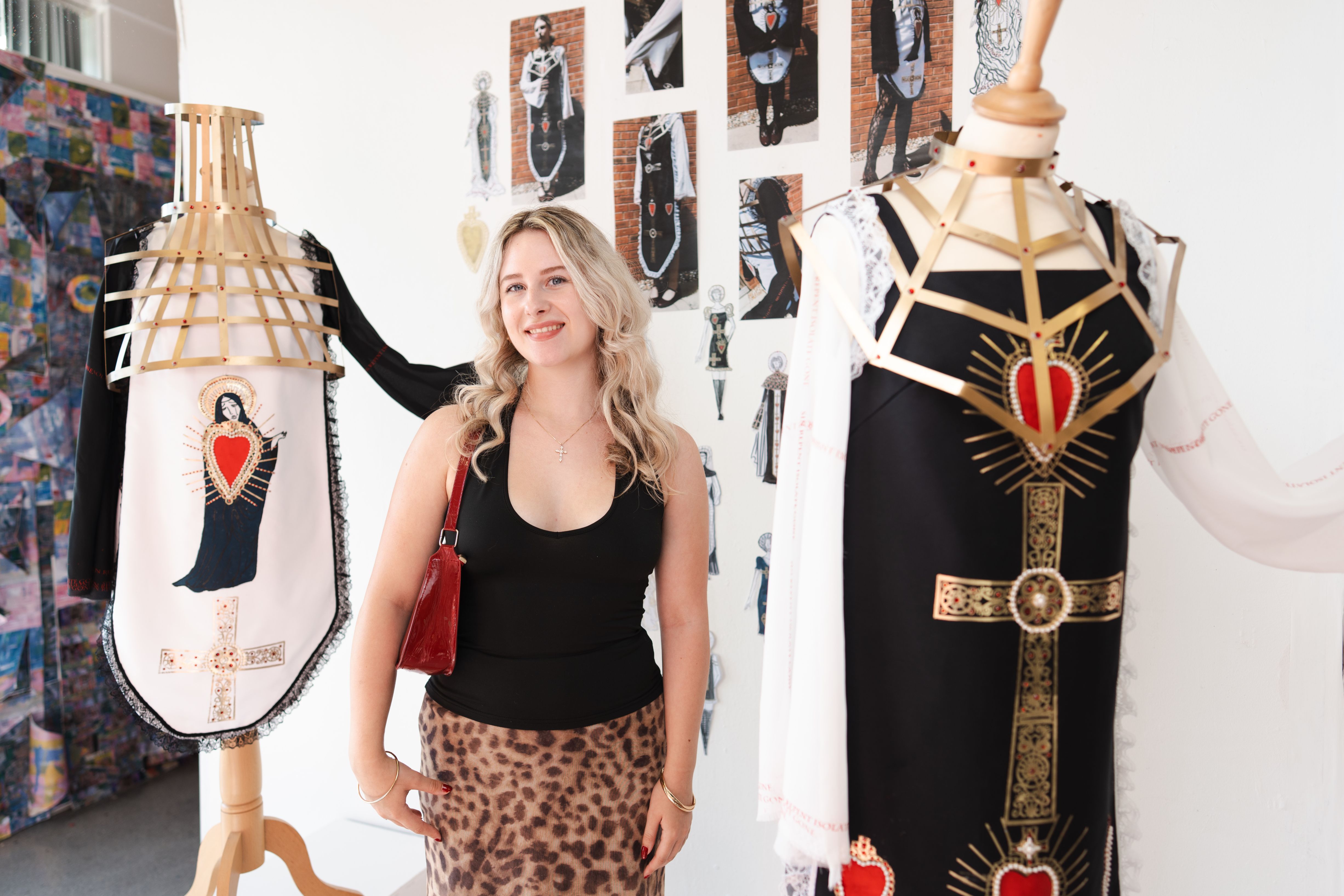 Student standing with her fashion designs