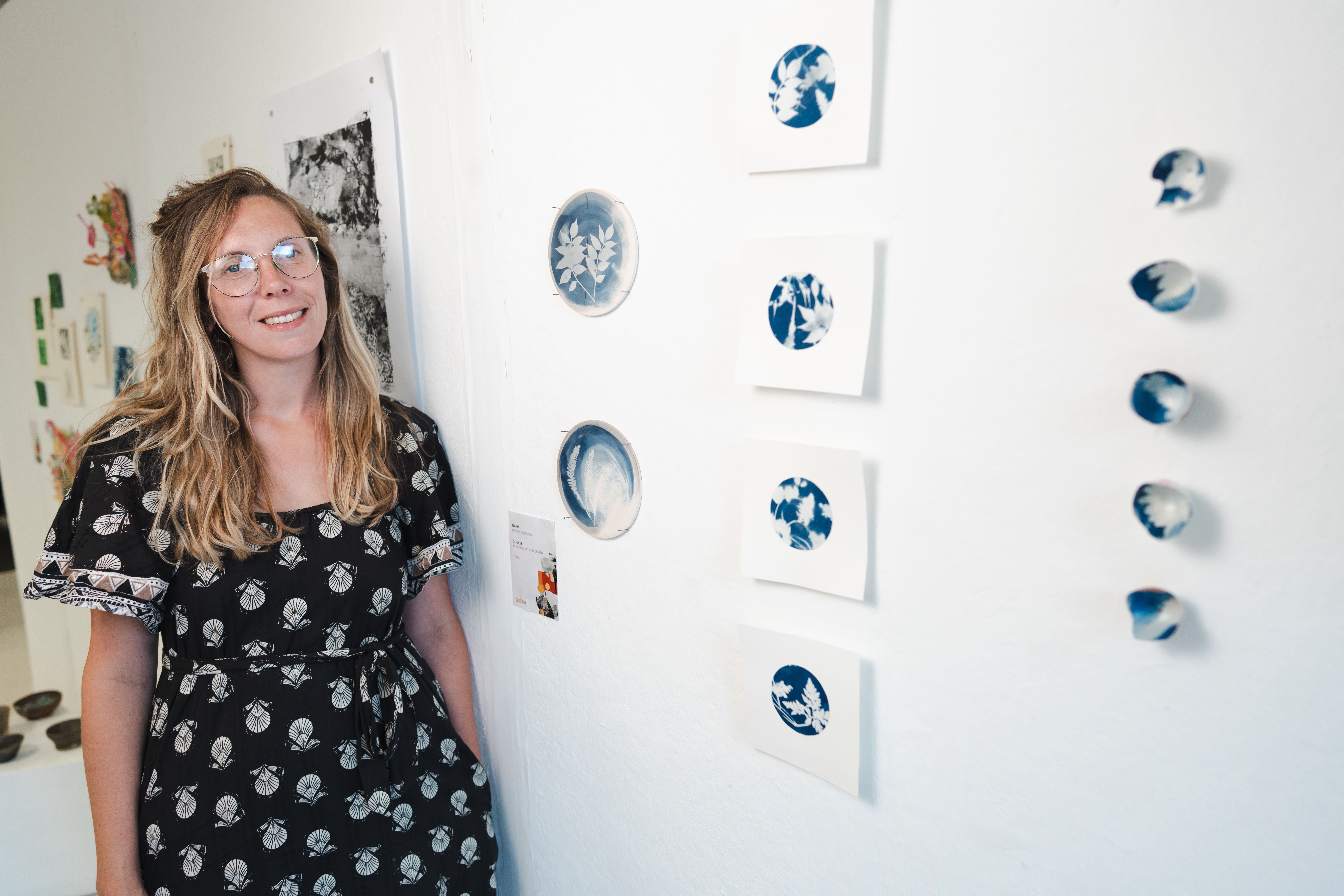 a women stands next to her circular blue paintings 