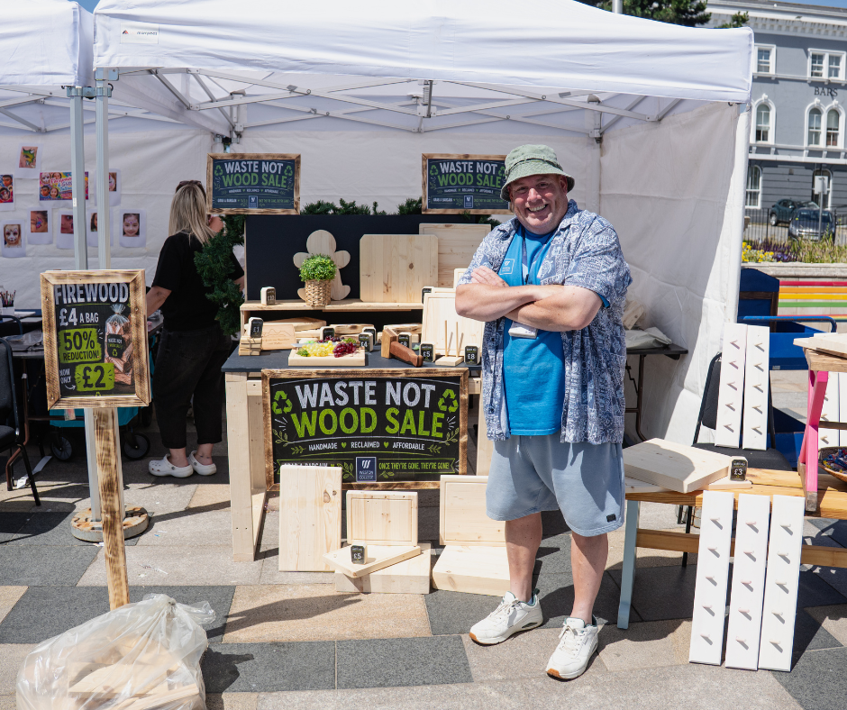 lecturer stood with carpentry pop up shop selling chopping boards and other wooden items