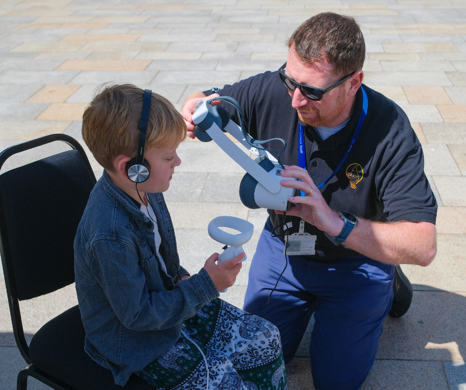 Attendees using VR headset with college staff