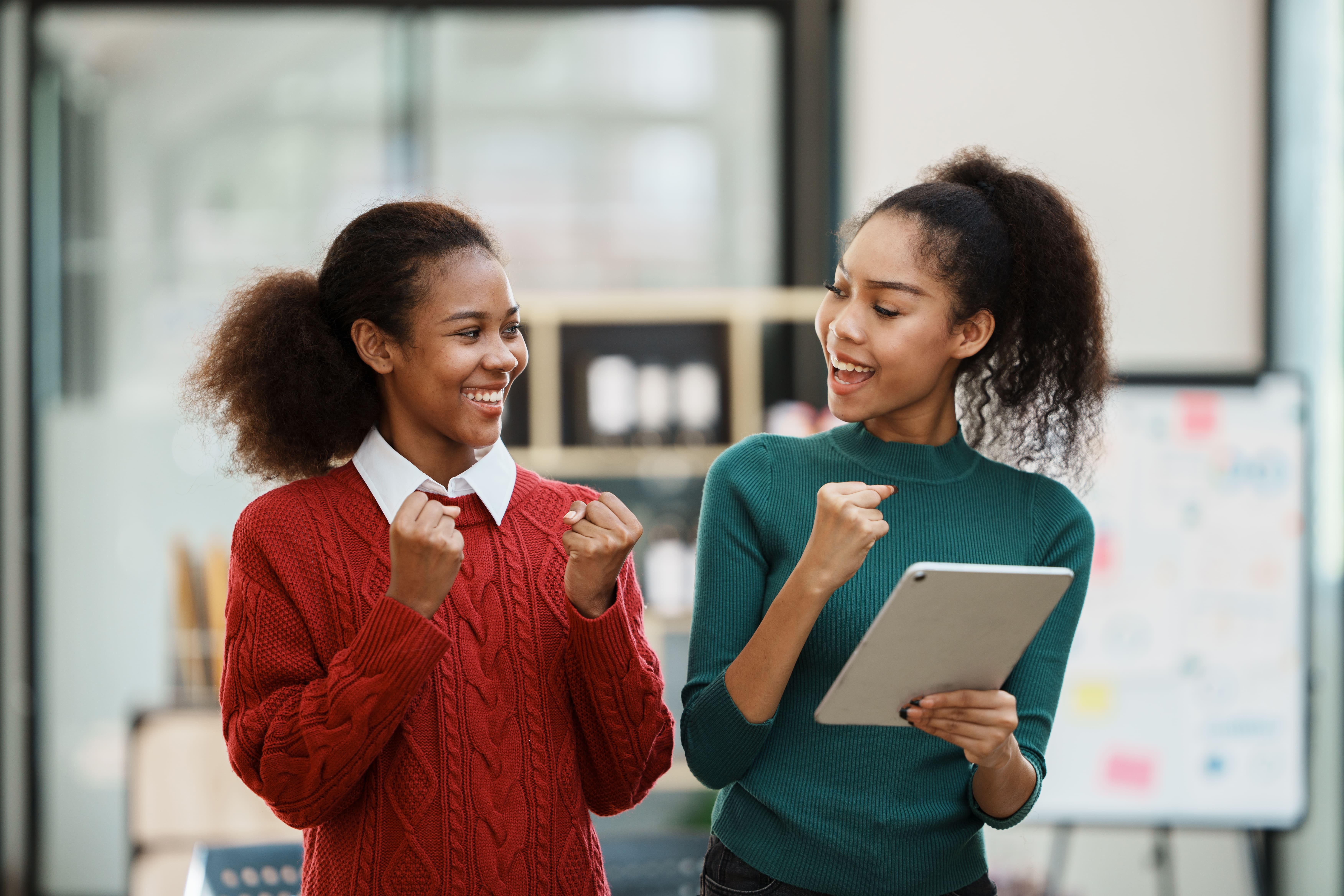 two women (one holding an iPad) cheer