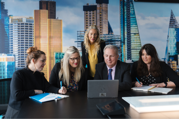 Five professionals analysing data on a laptop in a boardroom