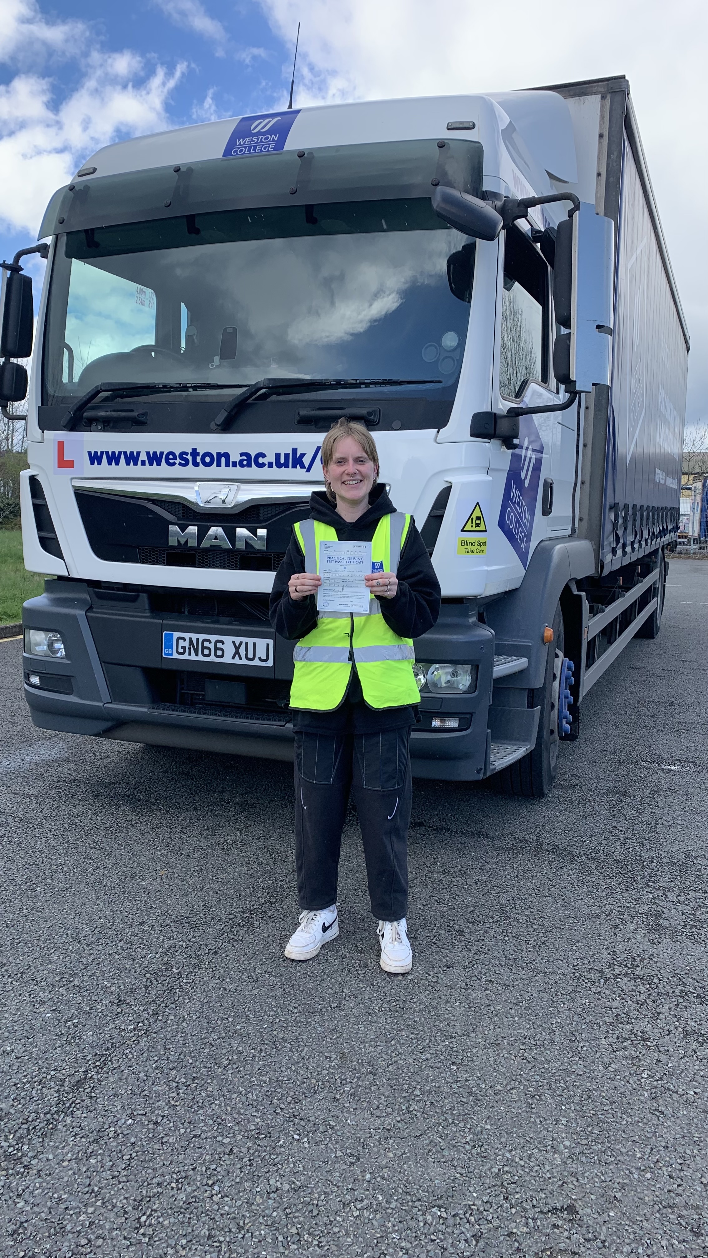 Jenny holding her certificate by the lorry