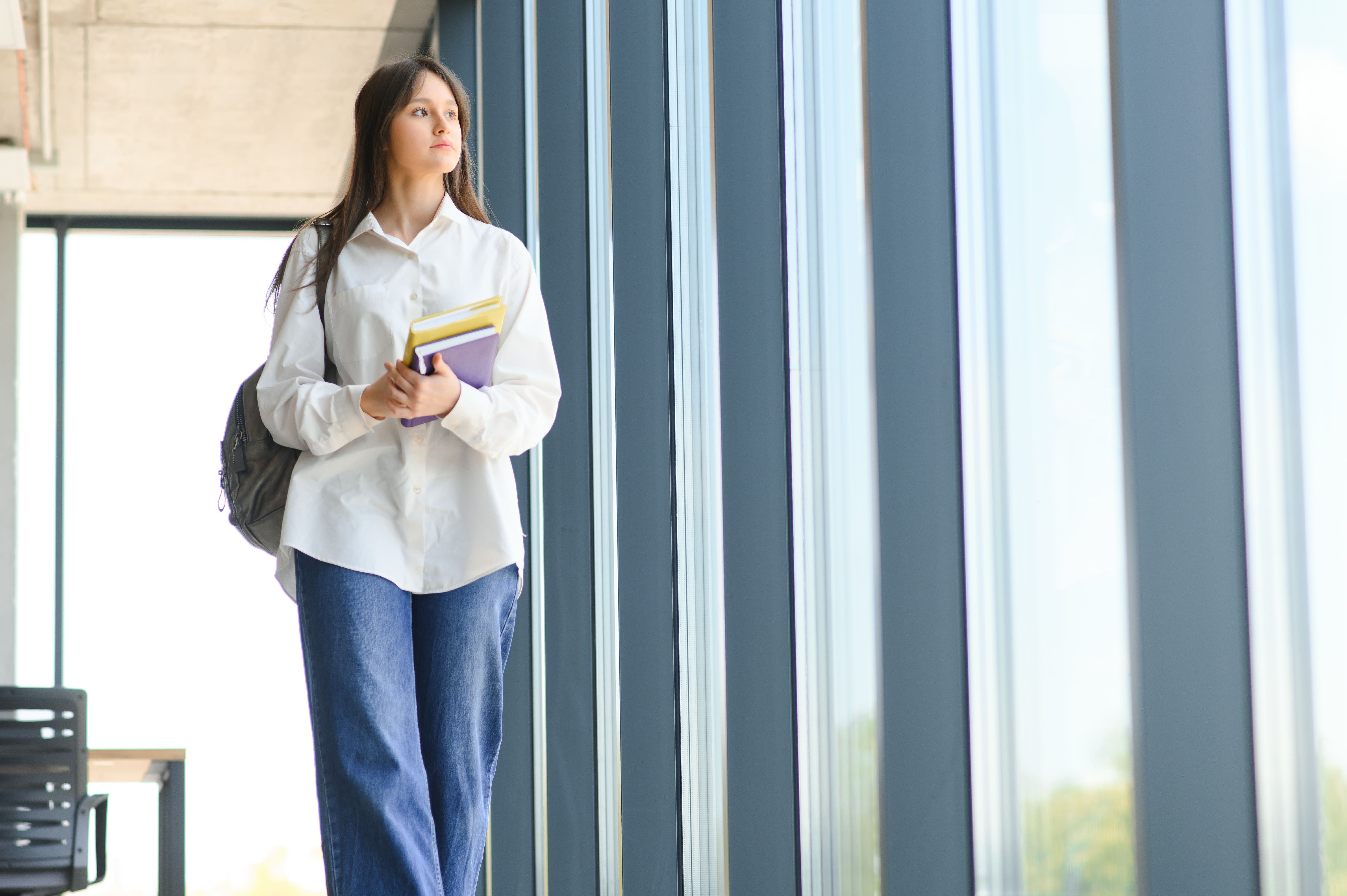 a schoolgirl stading with books and a backpack at school