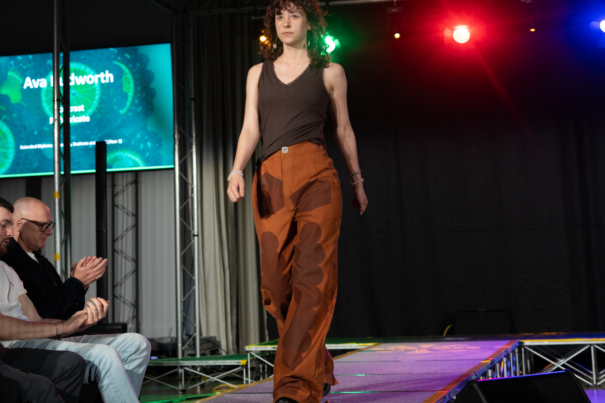 One of our models on the catwalk in orange trousers and brown top 