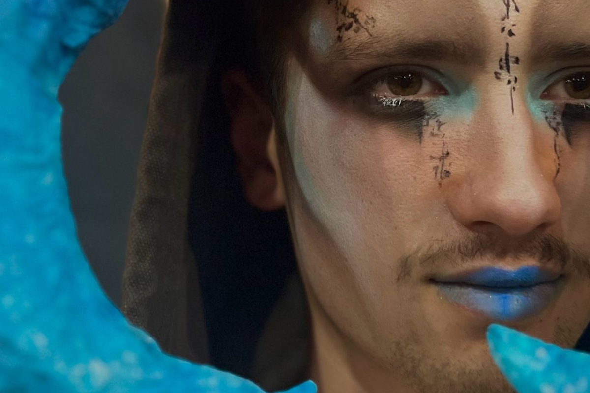 Student with fantasy makeup and face paint with blue horns 
