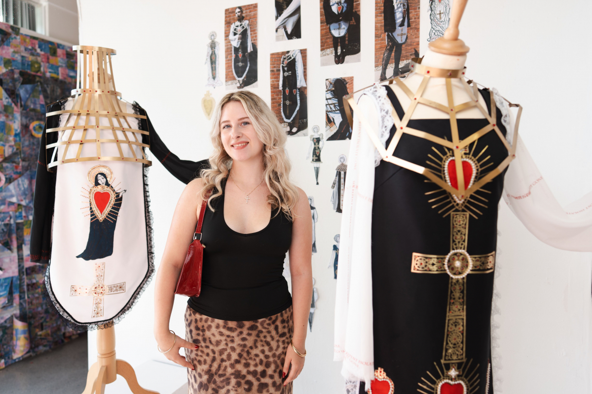 Student standing with her fashion designs