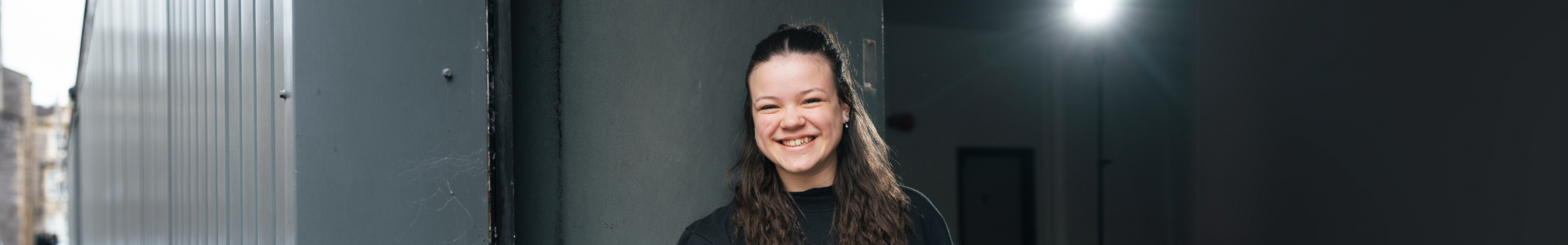 a girl leaning against a wall smiling