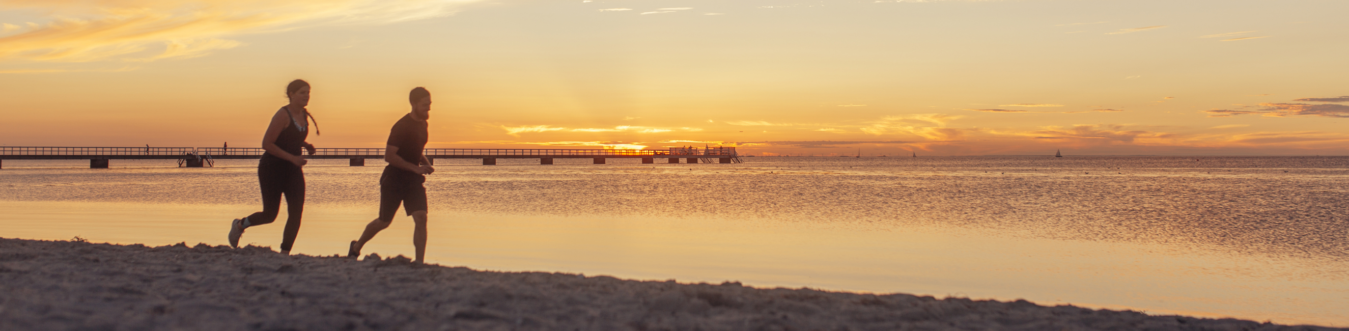 Two people running on the beach by a nice sunset