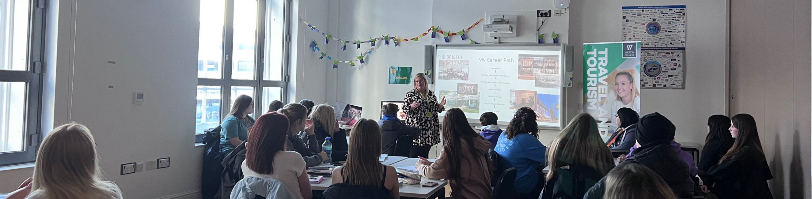 Lindsey delivering guest lecture at front of classroom and pointing to the board showcasing Mollies