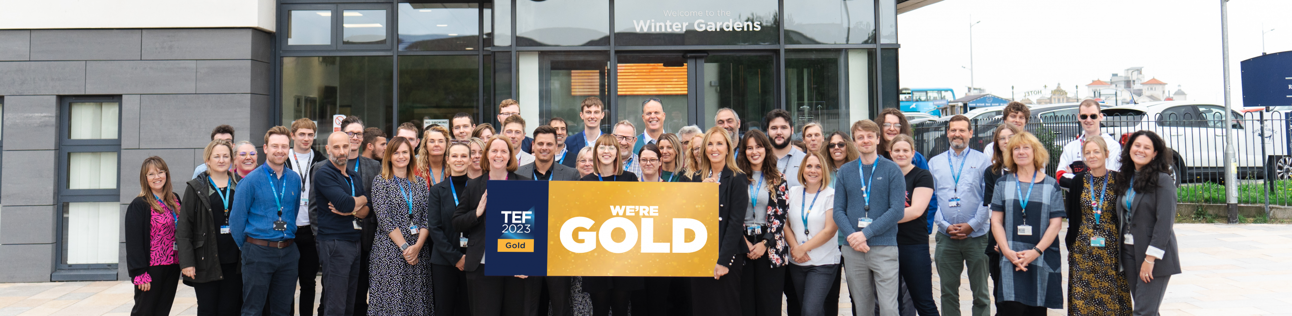 UCW staff holding a TEF Gold banner outside the Winter Gardens