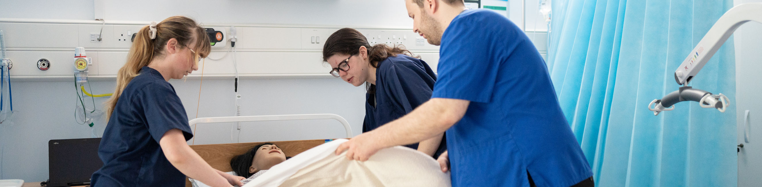 Students gathered around a nursing simulator