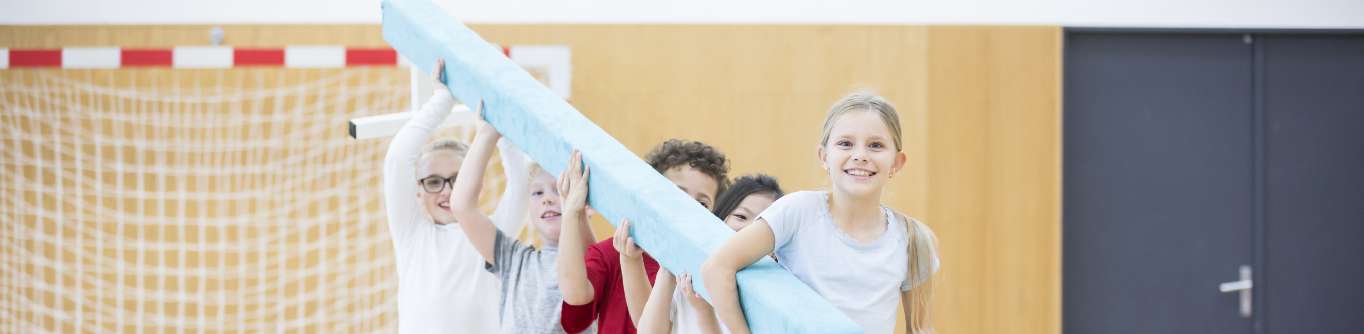 Students carrying balance beam in gym class