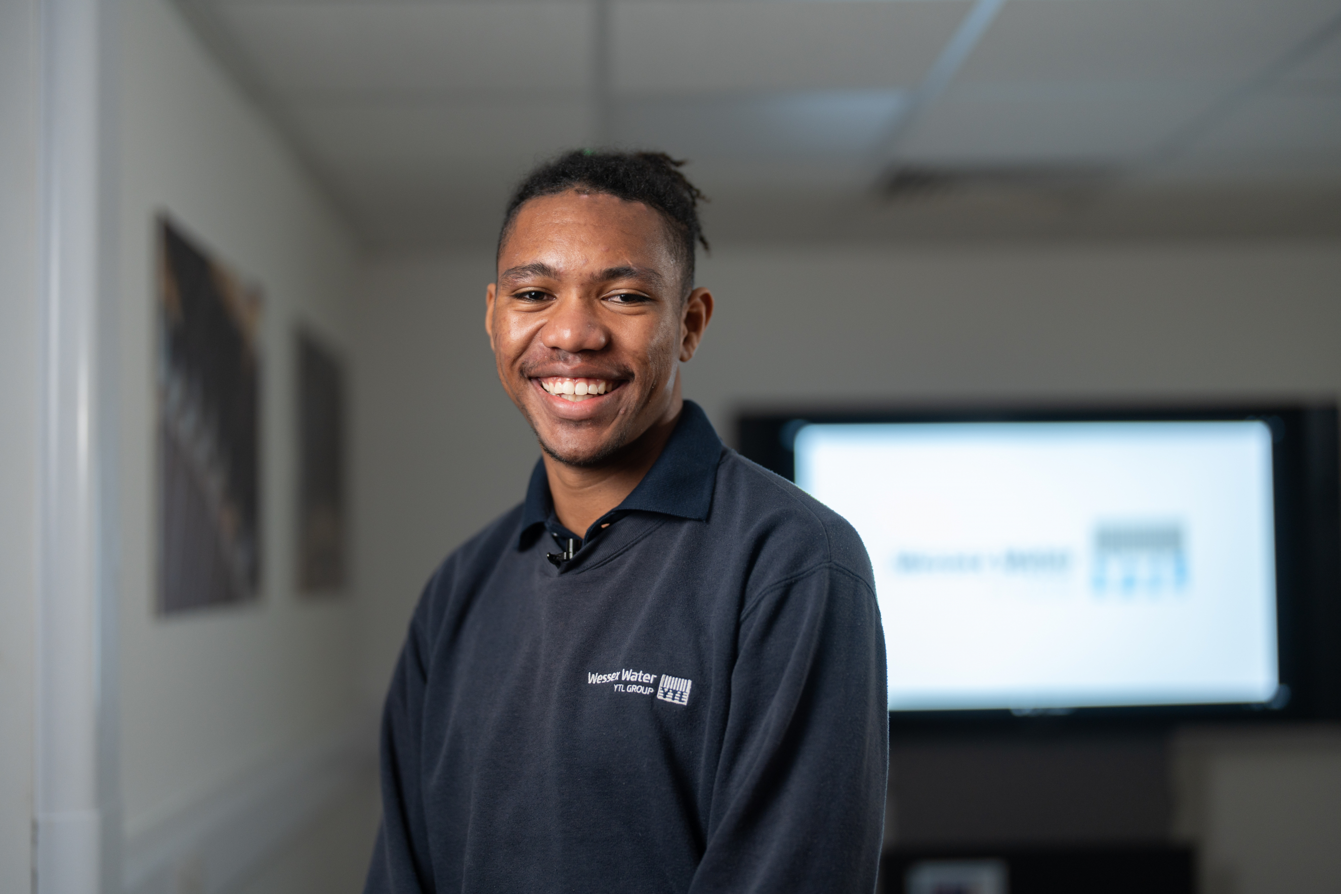 Learner stood facing the camera and smiling in their workplace