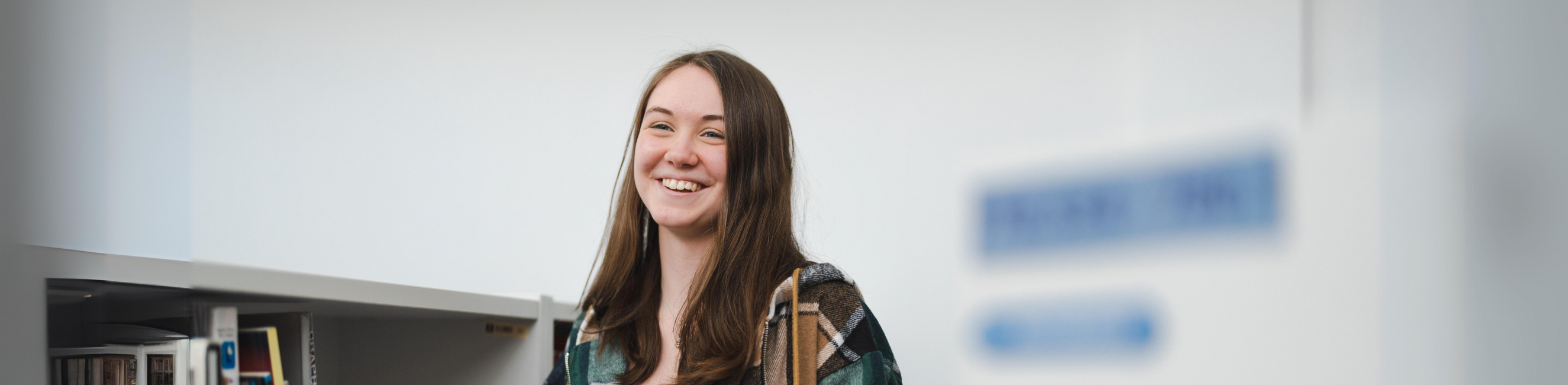 female student holding an open textbook and smiling