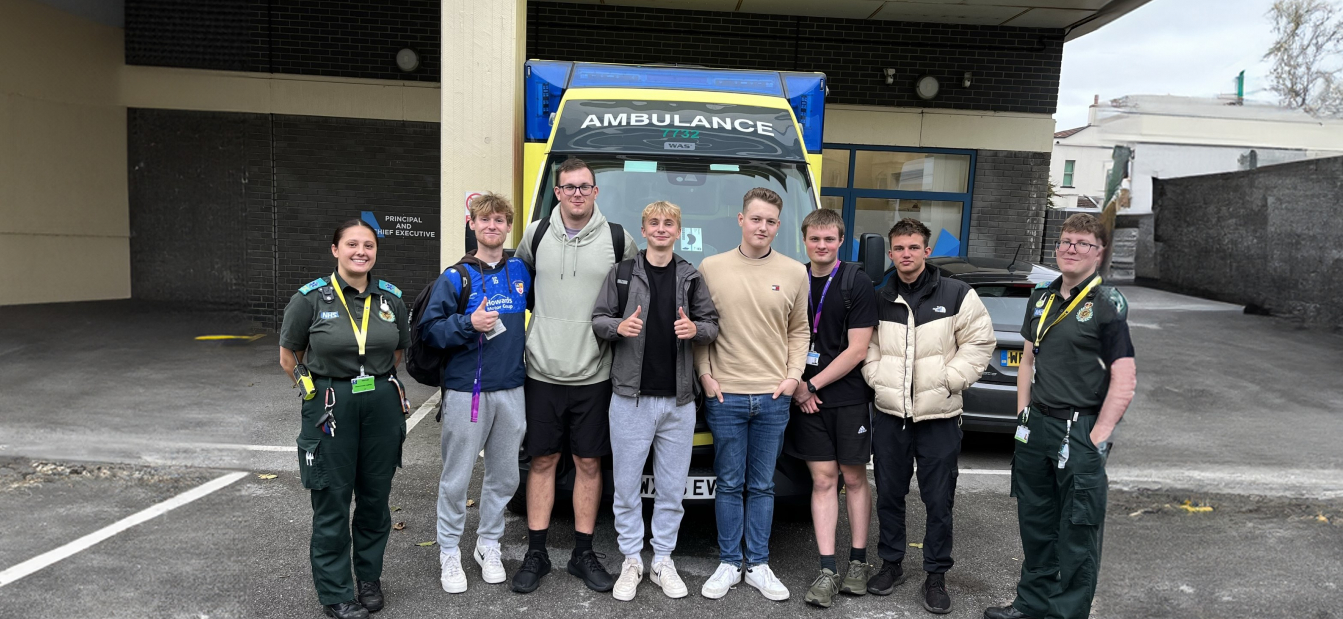 protective services students with former weston college students, now emergency care assistants, in front of ambulance
