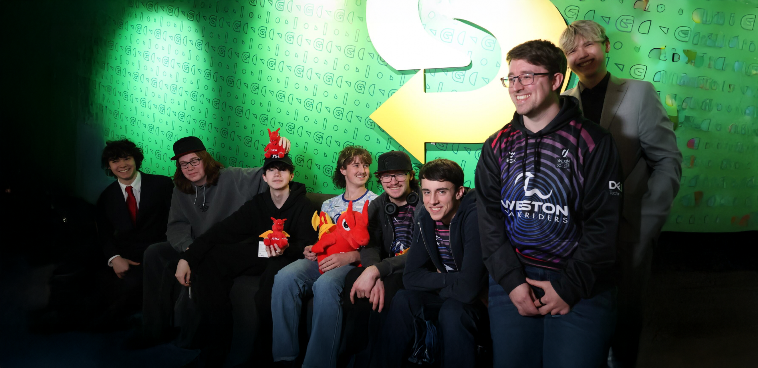 Esports students and lecturer group photo with their new dragon plushies from the tournament