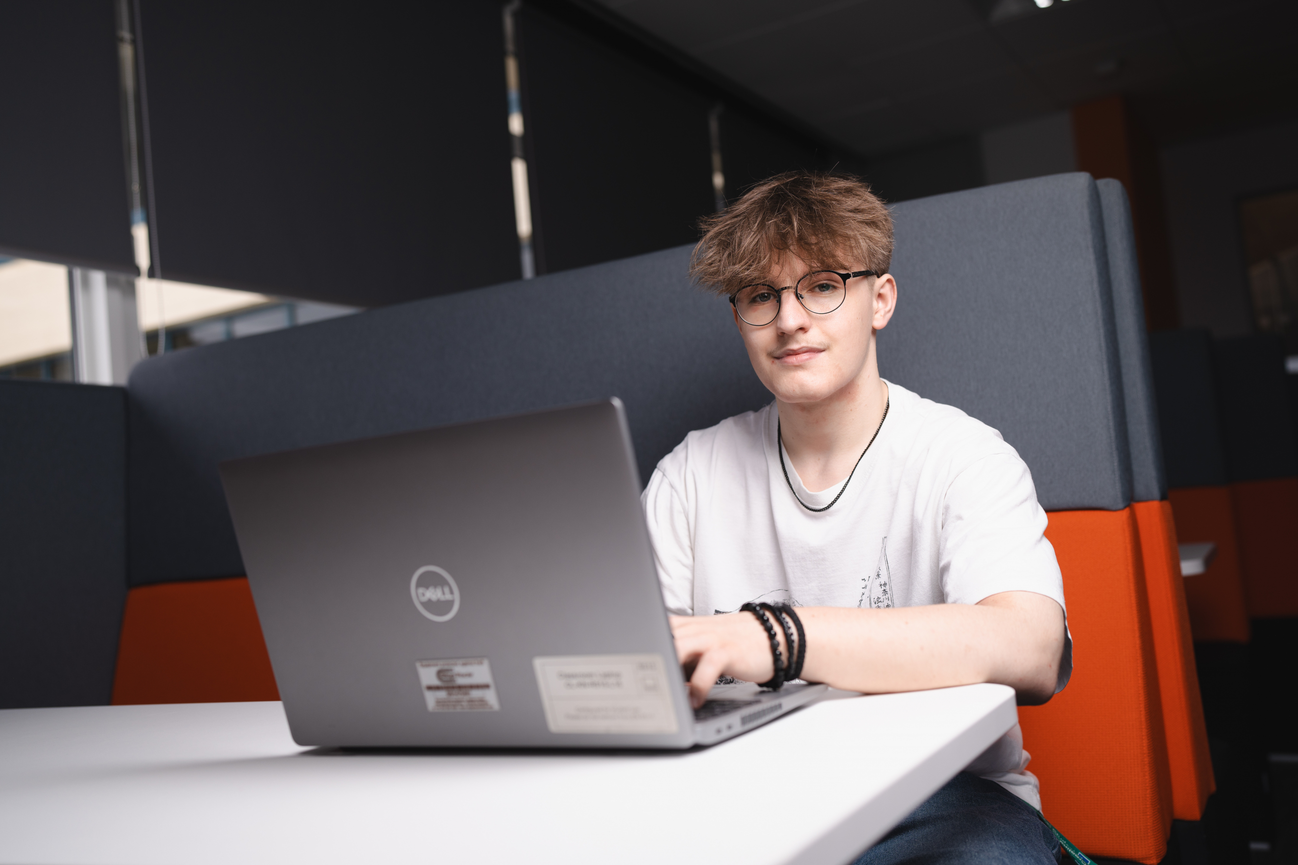 Student on laptop and smiling at the camera