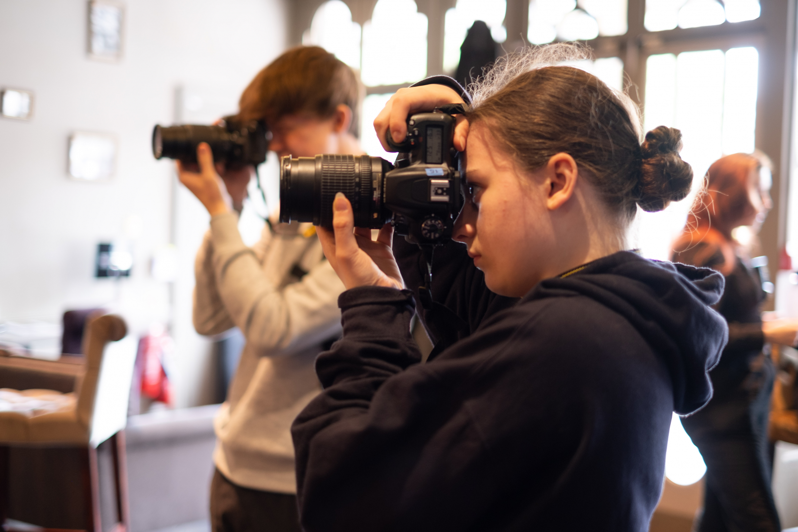 2 students looking through the lens of their camera taking a picture