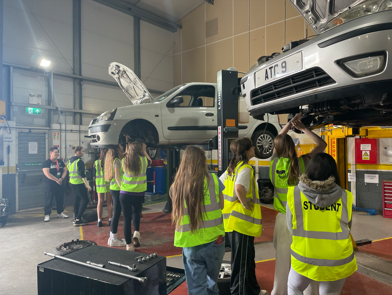 Students in Hi-Vis jackets fixing the underside of a car