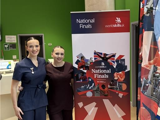 Maddie and Ellie standing by the WorldSkills banner