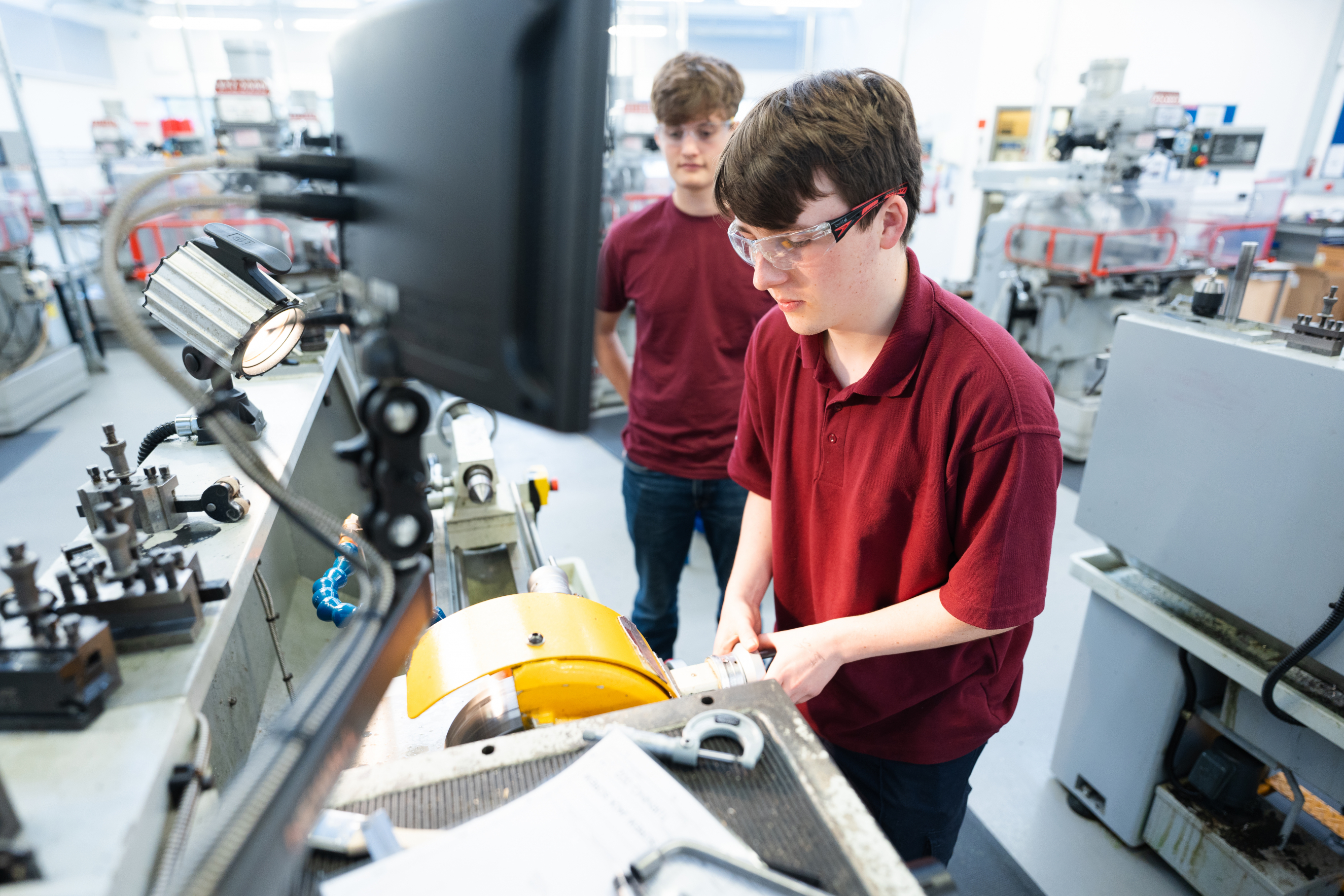 Two students working an engineering machine