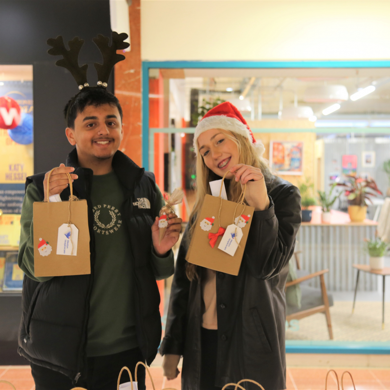 Two Business learners smiling at their stand and holding their product