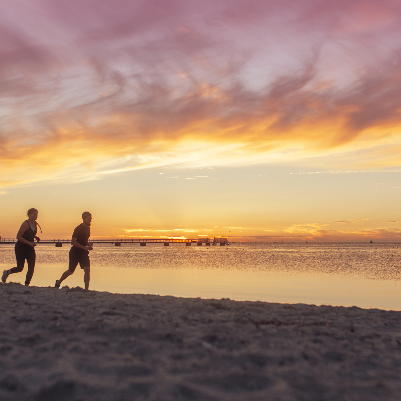 Two people running on the beach by a nice sunset