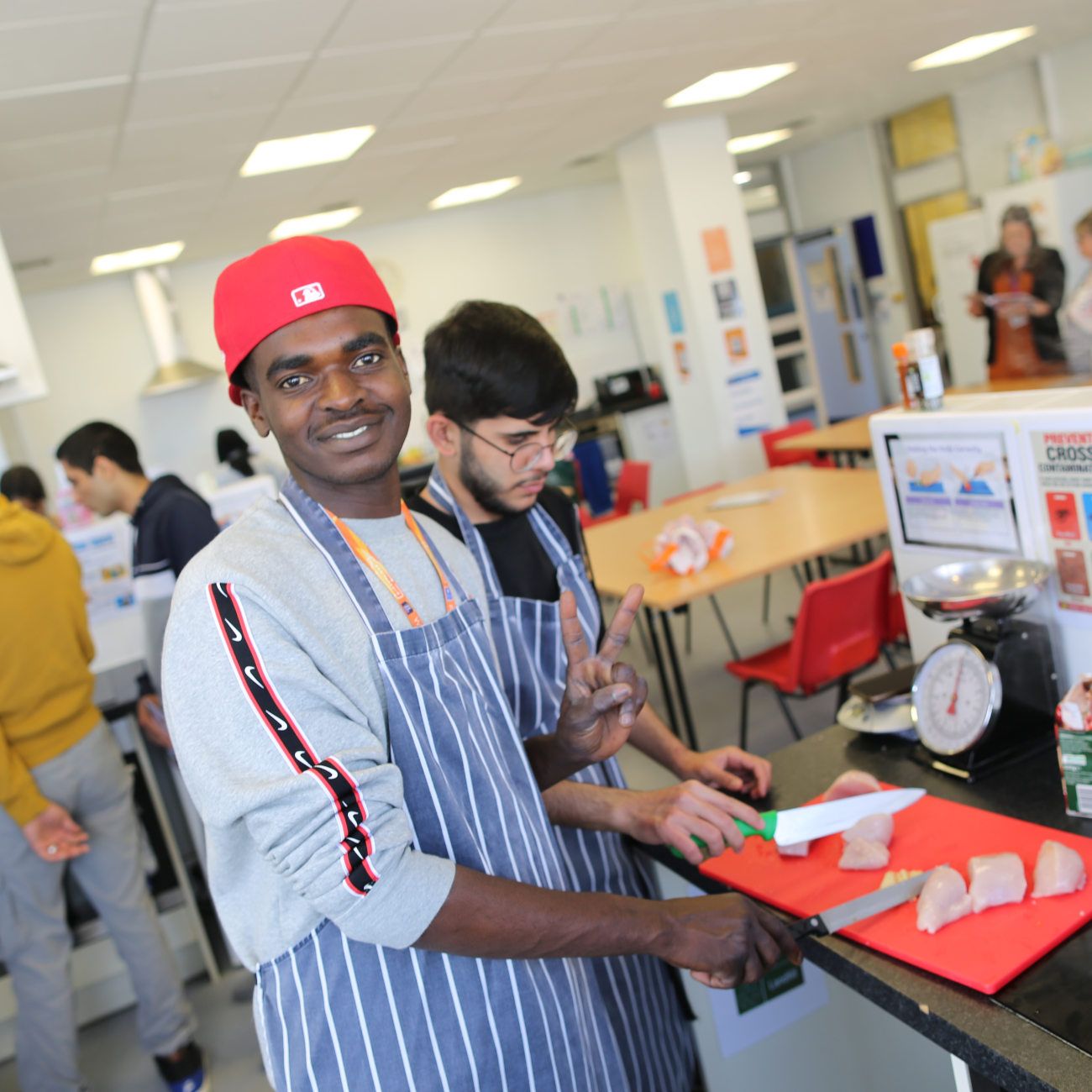 Learner smiling at camera whilst chopping up chicken 