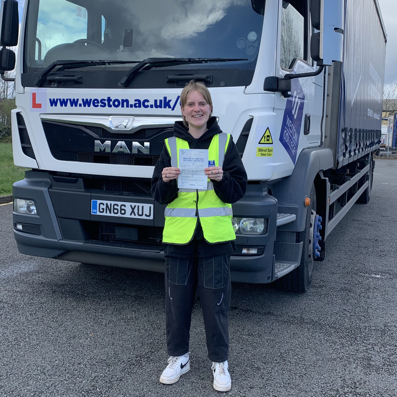 Jenny holding her certificate by the lorry