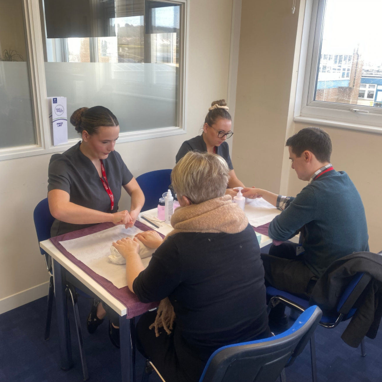 Beauty students giving hand treatments to worle school staff