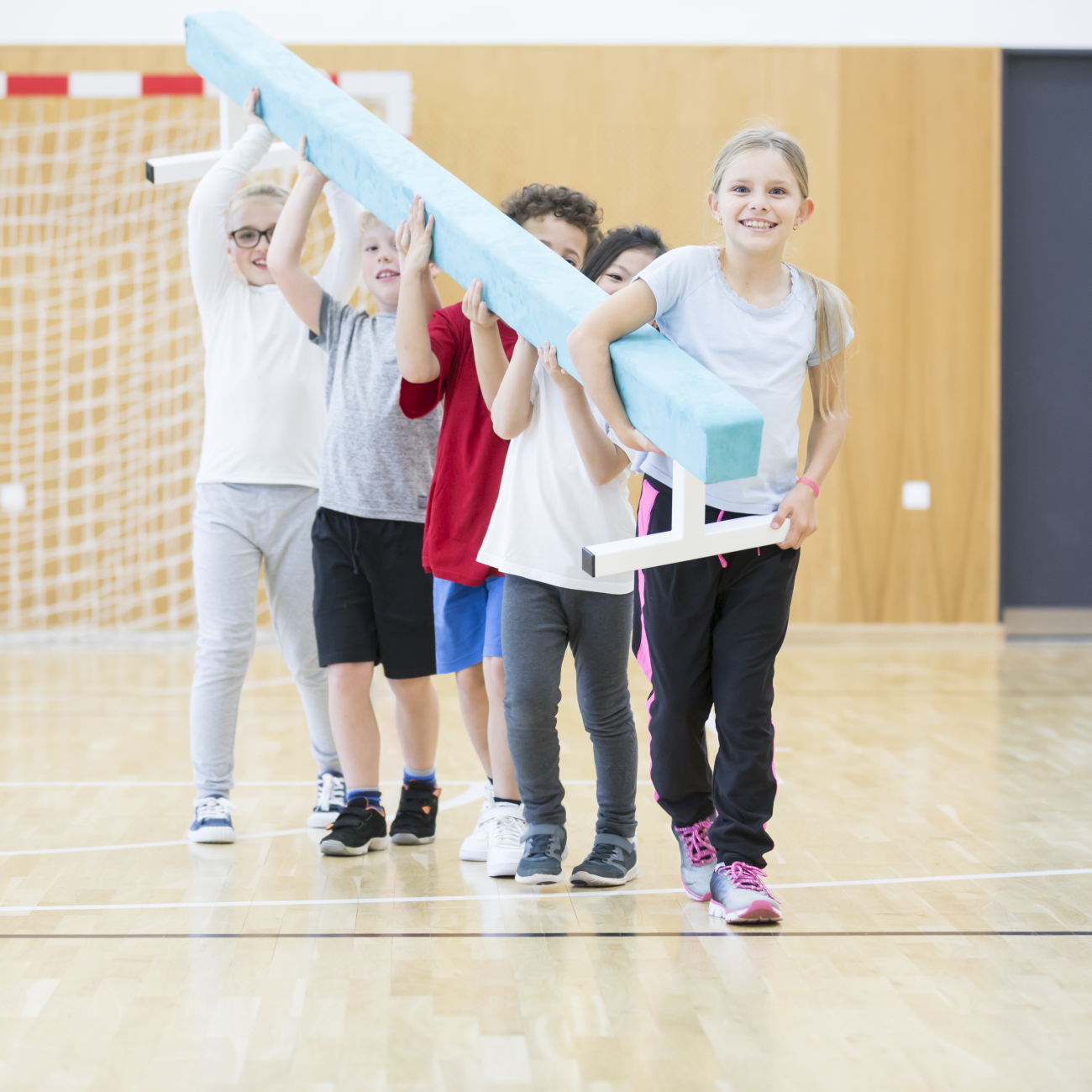 Students carrying balance beam in gym class