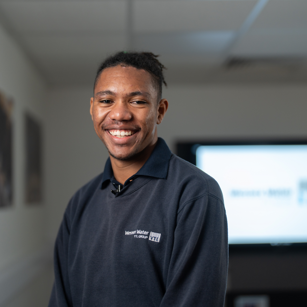 Learner stood facing the camera and smiling in their workplace