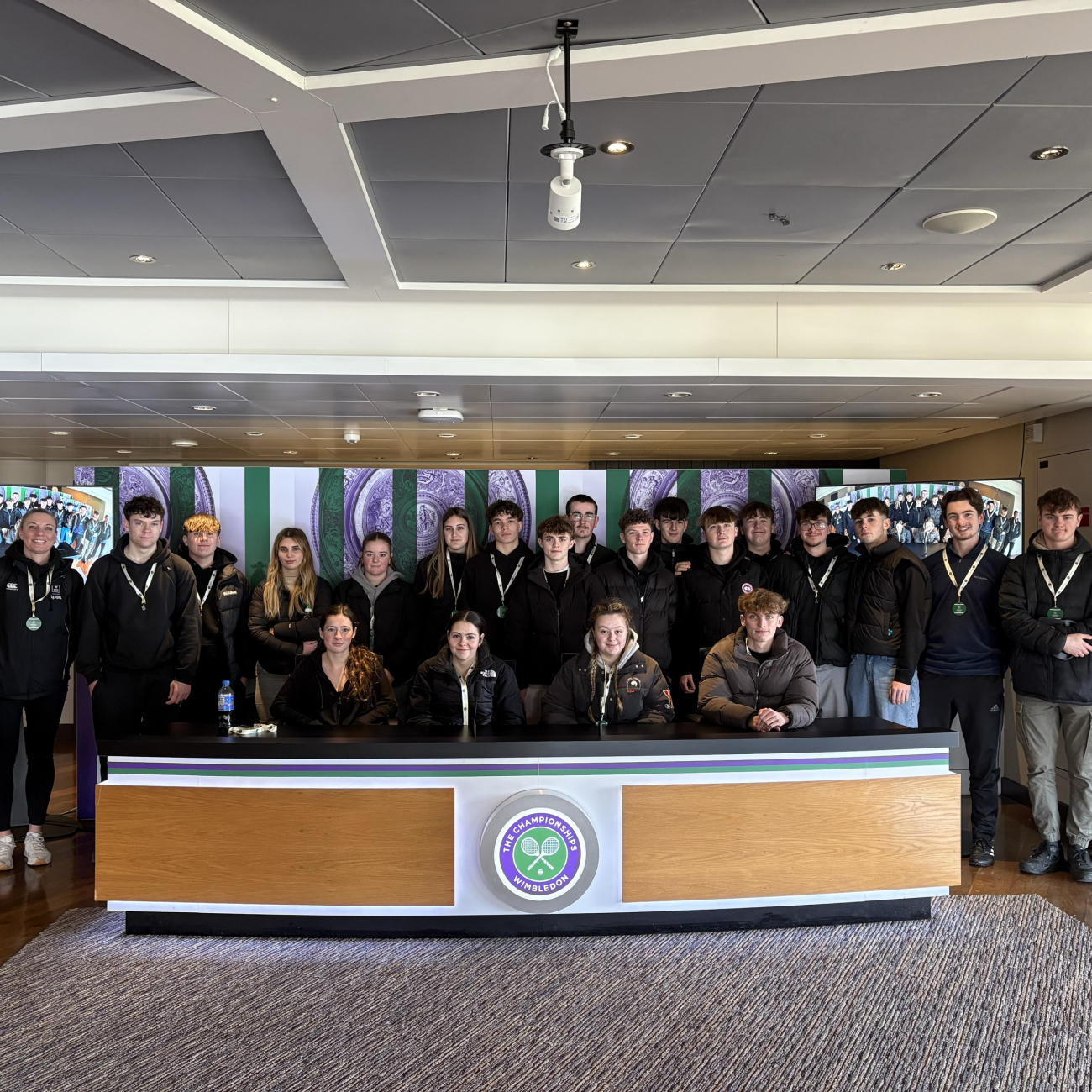 Sport students standing behind the Wimbledon spectator desk