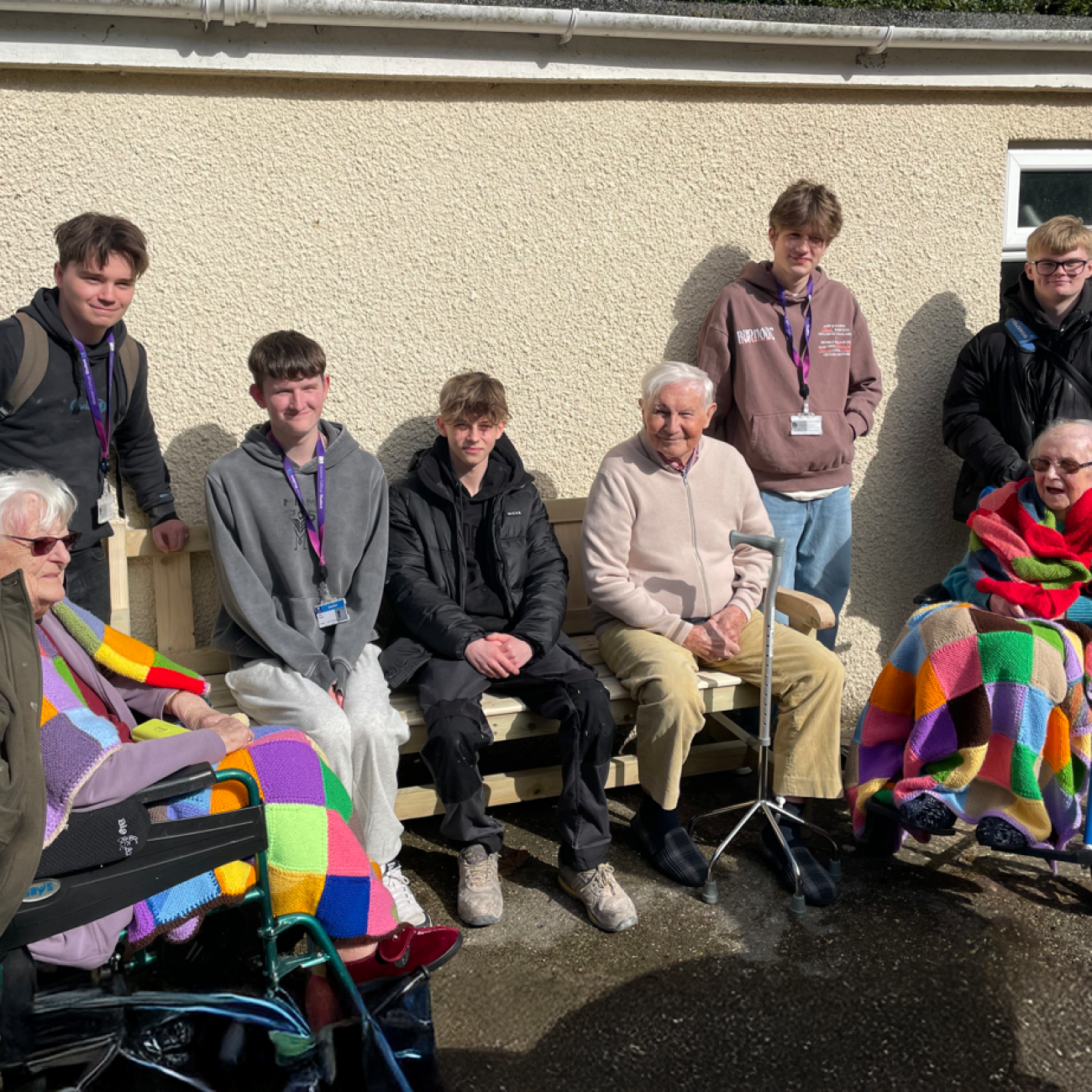 5 students and 3 residents sat on and around the bench smiling