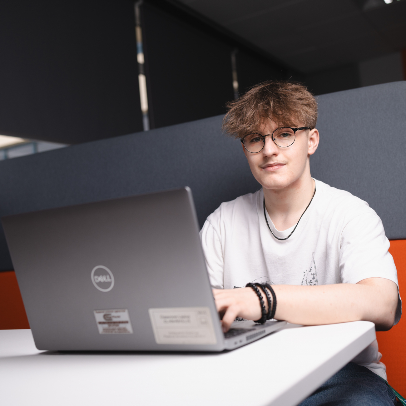 Student on laptop and smiling at the camera