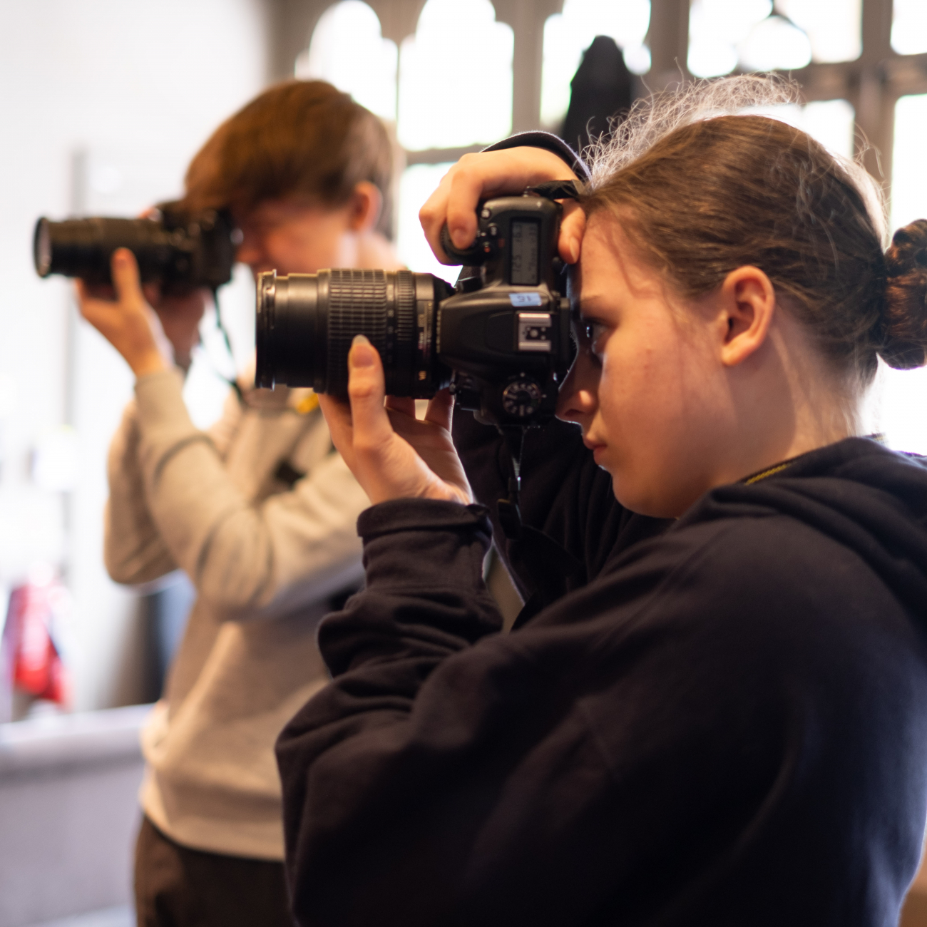 2 students looking through the lens of their camera taking a picture