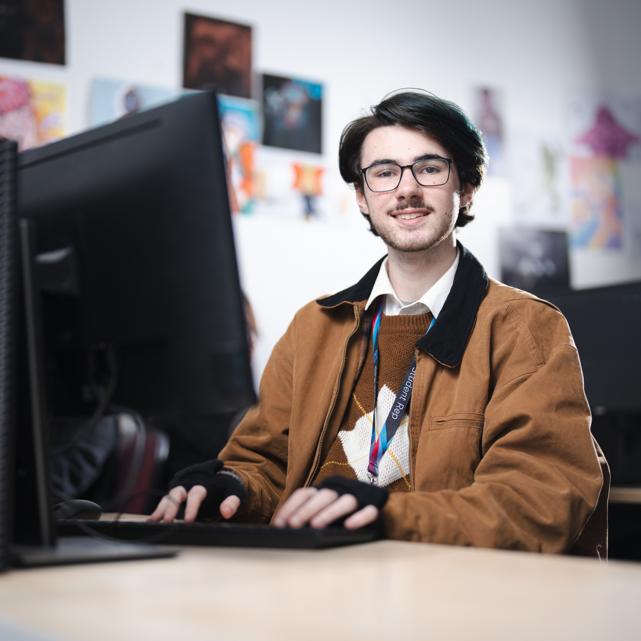 Learner smiling at the camera as he works on a computer