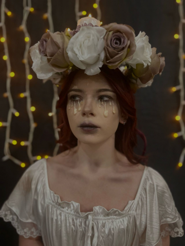 Student wearing a flower headdress with foundation dripping from her eyes