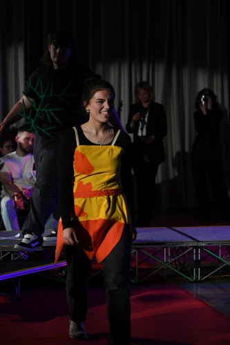 One of our models smiling in a yellow and orange jumpsuit